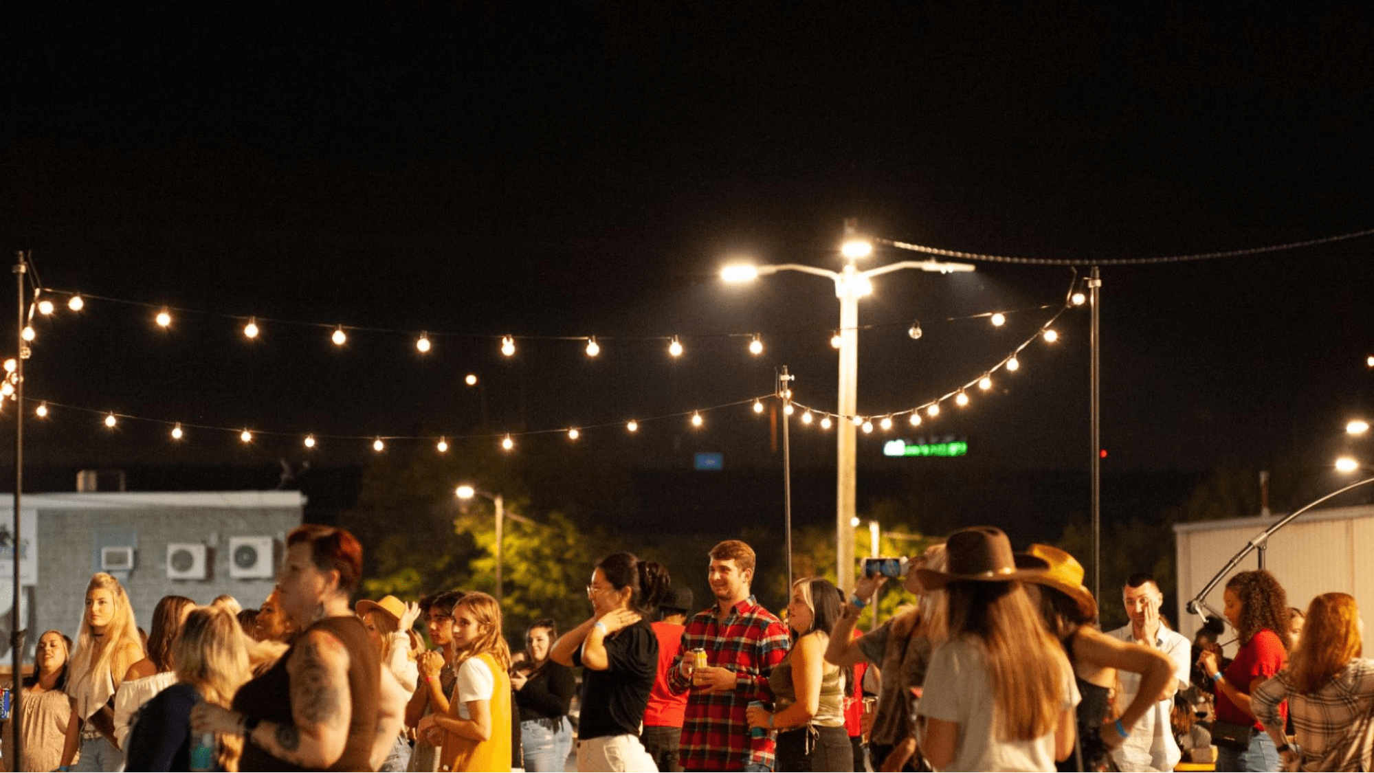 People at a party below string lights