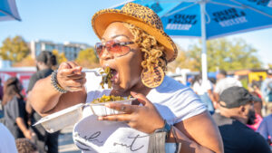 Female attendee eating at the Black Food Truck Festival