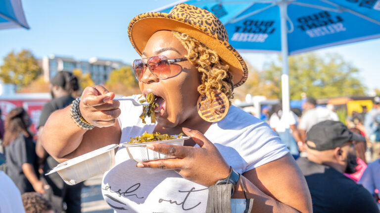 Female attendee eating at the Black Food Truck Festival